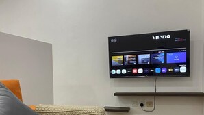 Una moderna camera d'albergo con una TV a schermo piatto montata a parete che mostra l'interfaccia di un servizio di streaming.
