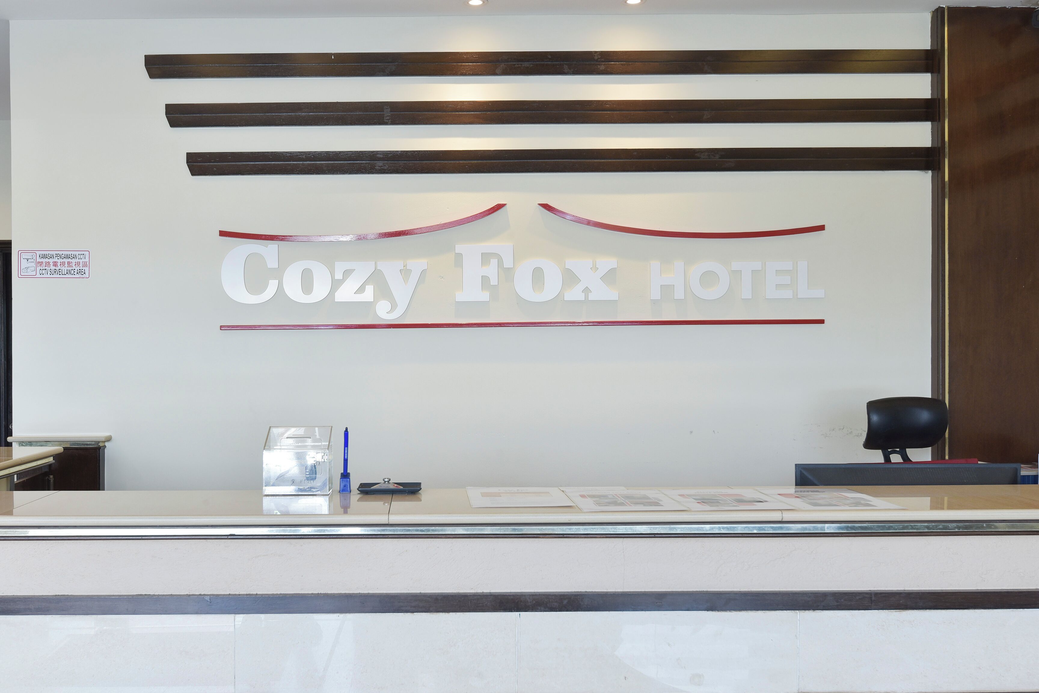 Un comptoir d’accueil avec une enseigne indiquant : « Hôtel Cozy Fox ».