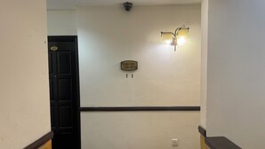 A hallway with a door marked 203, a wall-mounted light fixture, and a small plaque with numbers. - Hotel O Cozy Fox Hotel (Petaling Jaya)