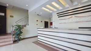 A reception area with a reception desk, a staircase, and a potted plant. - Hotel O Cozy Fox Hotel (Petaling Jaya)