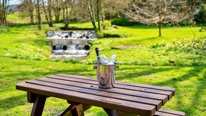 A picnic table with a metal container holding a bottle and glasses. - Cottage in Thirsk with Scenic Trails & Spa (Thirsk)