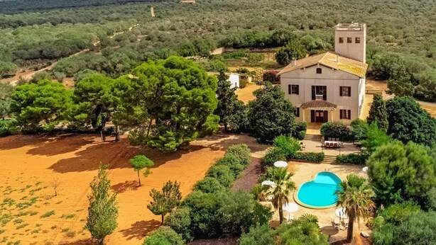 Eine Villa mit Schwimmbad, umgeben von üppiger Vegetation und einer Wüstenlandschaft.