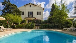 Ein Pool mit Liegestühlen und ein Gebäude mit Balkon im Hintergrund.