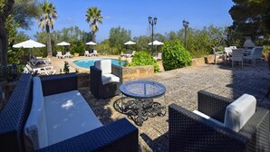Ein Poolbereich mit Liegestühlen, Sonnenschirmen und einem runden Tisch.