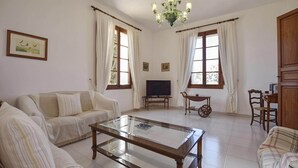 Ein Wohnzimmer mit einer Couch, einem Couchtisch, einem Fernseher und einer Chandelier.