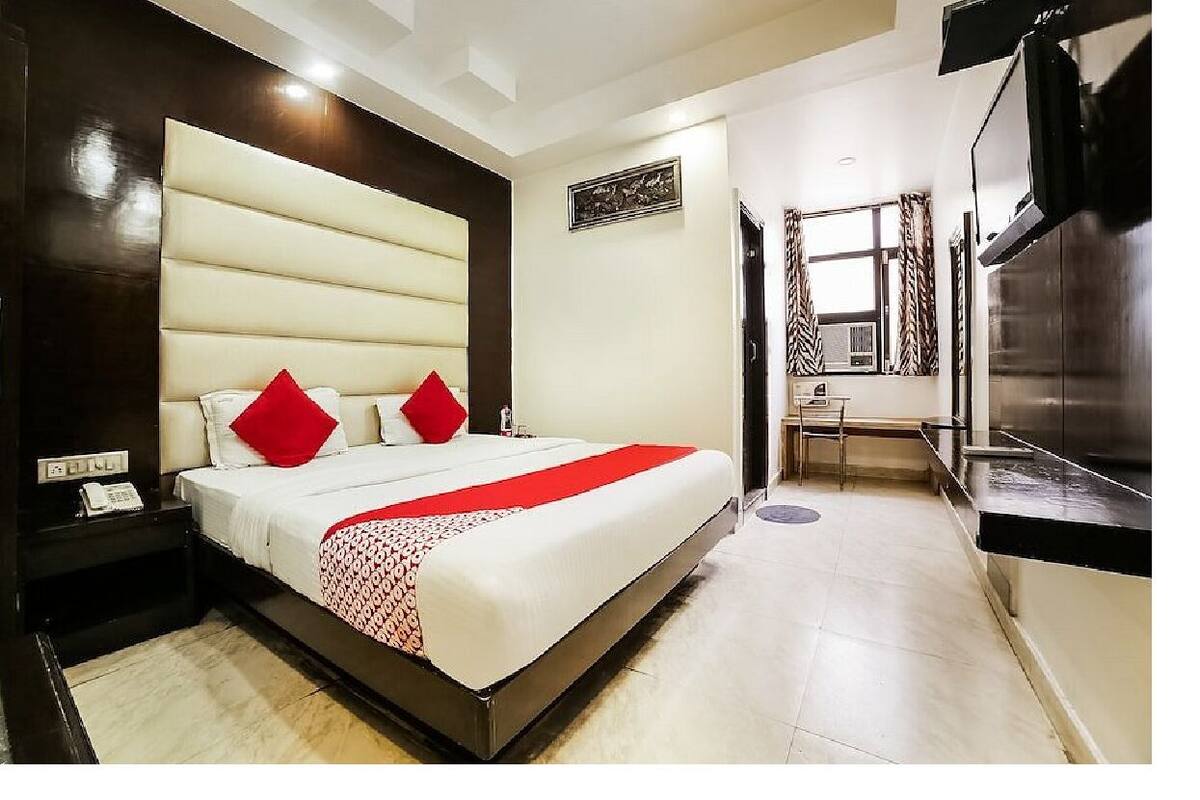 Ein Hotelzimmer mit einem großen Bett, einem Schreibtisch, einem Fernseher und einer Minibar.