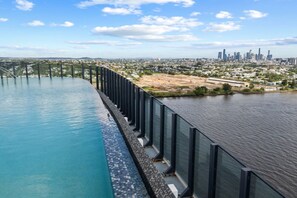 A pool with a glass barrier and a view of a city skyline.