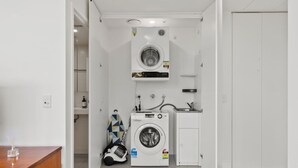 Ein kleiner Hauswirtschaftsraum mit zwei Waschmaschinen, einem Trockner und einem kleinen Waschbecken.