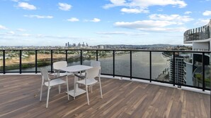 Ein Balkon mit Tisch und Stühlen mit Blick auf einen Fluss und die Stadtlandschaft.