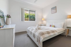Camera da letto con un letto, comodino, lampada e una finestra vista sul verde.