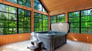 Un jacuzzi en una habitación con ventanas amplias y pisos de madera.