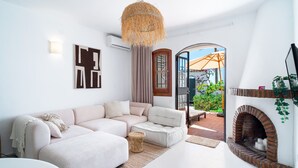 Un salon moderne avec un canapé d’angle, une cheminée et une vue sur la terrasse extérieure.