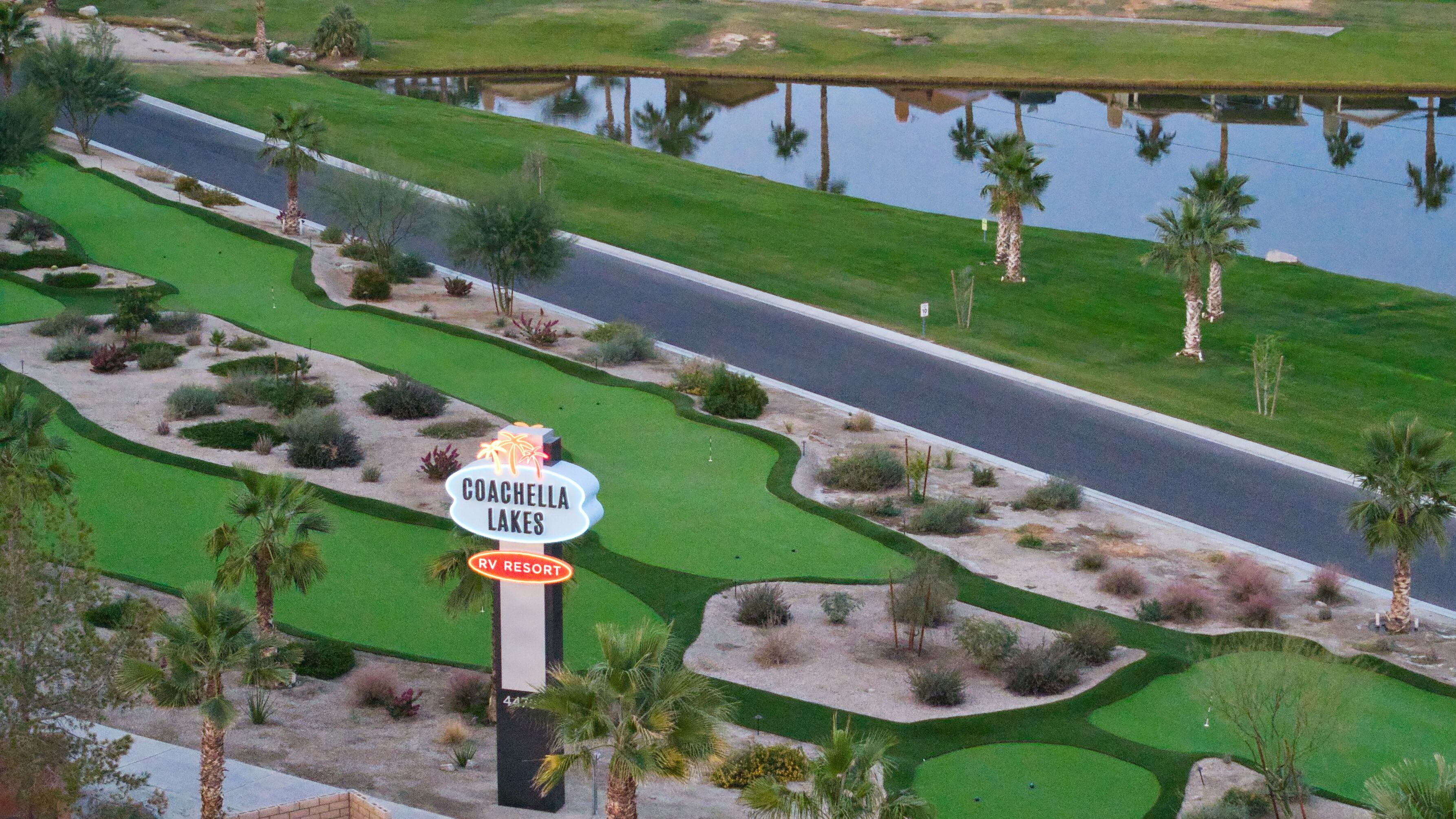 A golf course with a sign for Coachella Lakes RV Resort.