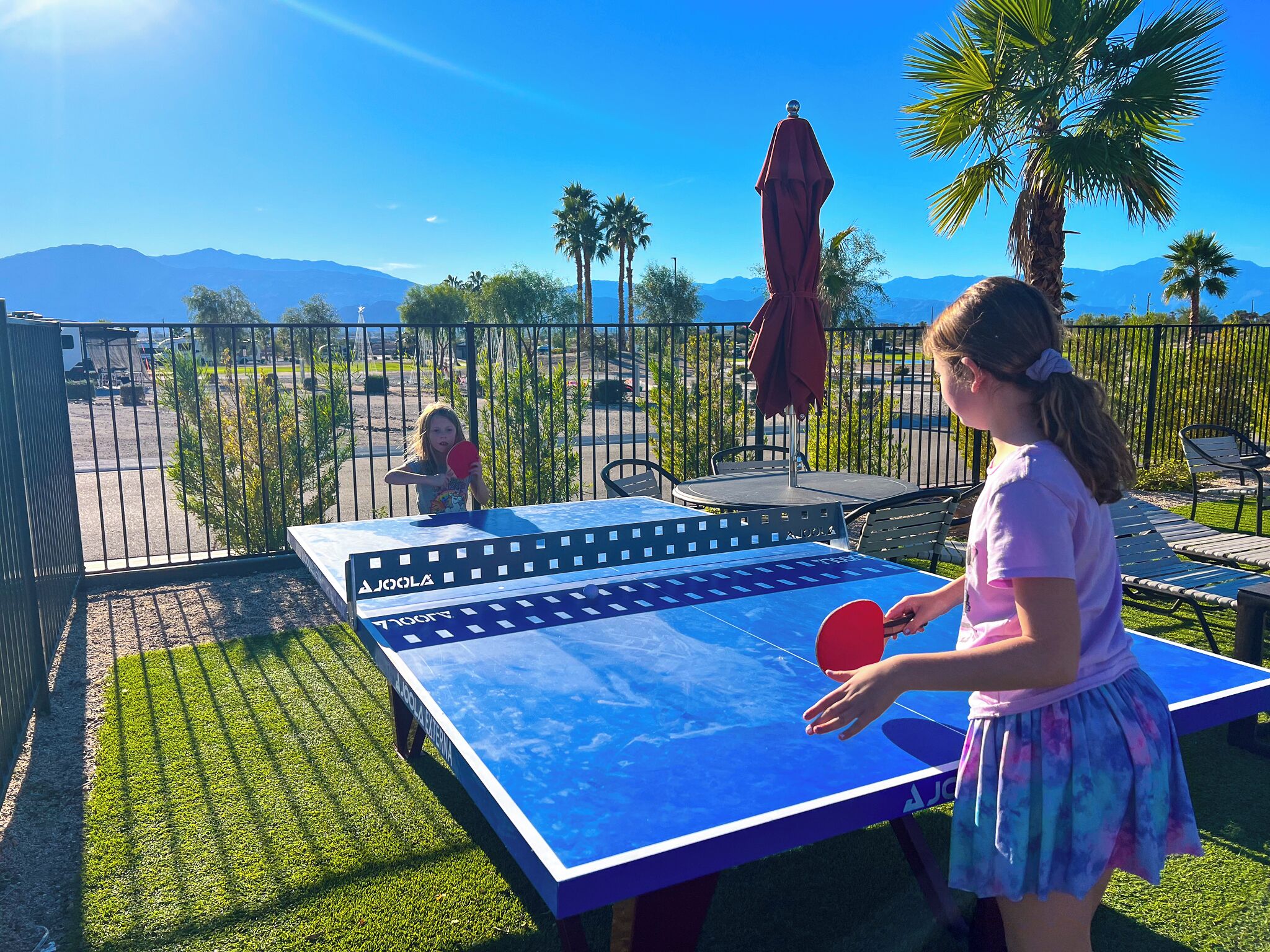 Mesa de ping pong al aire libre con una vista despejada de montañas al fondo.