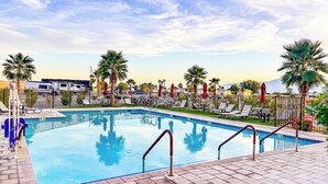 A swimming pool with lounge chairs and palm trees. - Coachella Lakes RV Resort (Coachella)