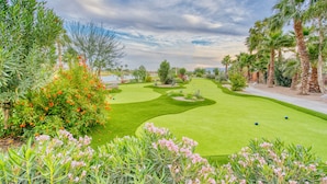 A golf course with a water hazard, palm trees, and a variety of shrubs and flowers. - Coachella Lakes RV Resort (Coachella)