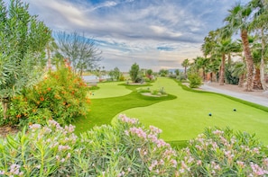 Ein Golfplatz mit einem Wasserhindernis, Palmen und verschiedenen Sträuchern und Blumen.