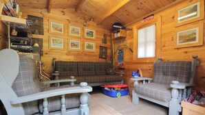 A cozy cabin interior with a sofa, two armchairs, a small table, and a wooden ceiling. - Apartment in a chalet nestled in the forest, with sauna and private forest (Canal San Bovo)