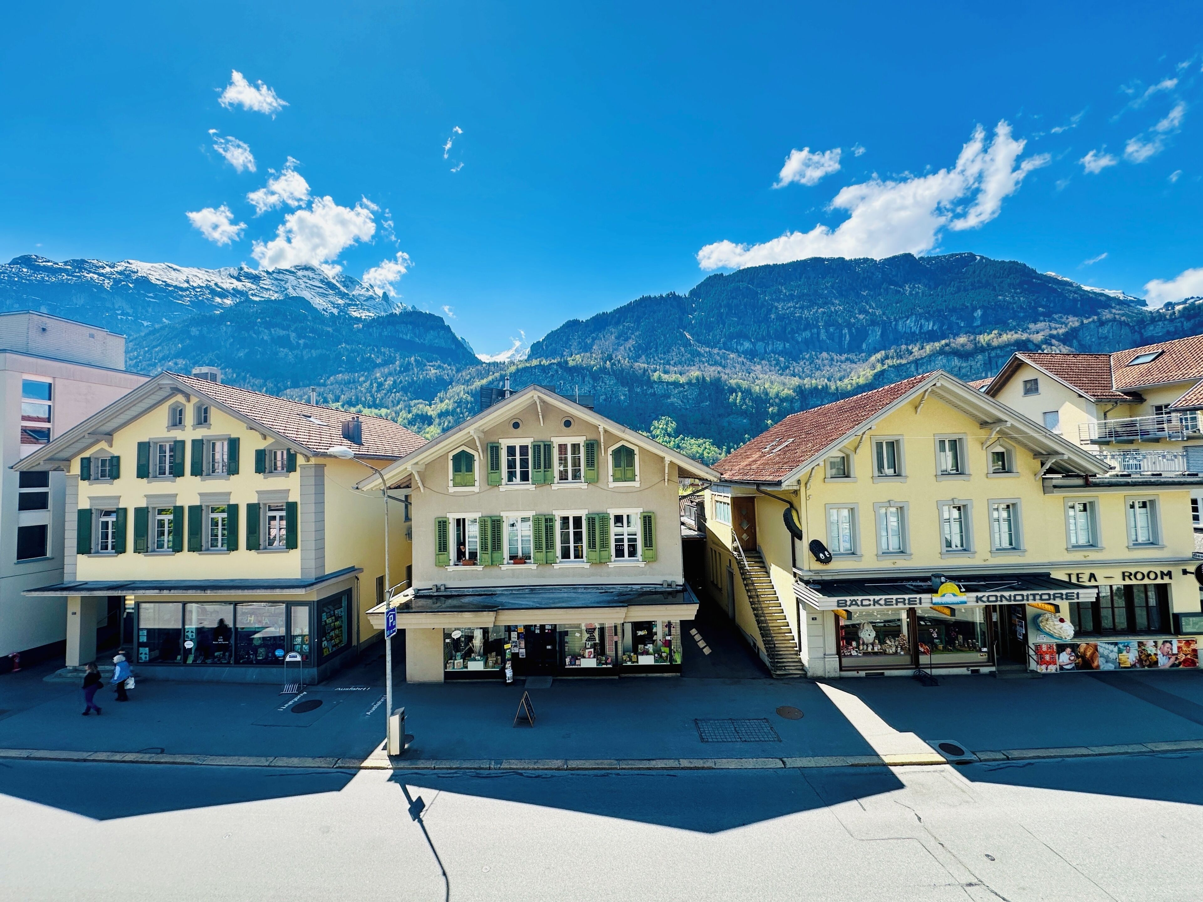 A street with buildings, a parking sign, and a mountain in the background.