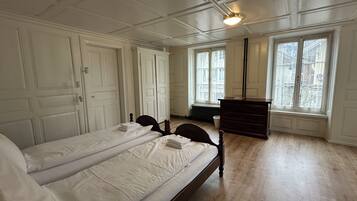 Una habitación con dos camas, un aparador y ventanas amplias.