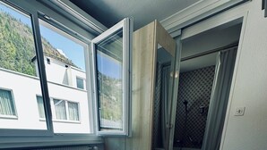 Ein Hotelzimmer mit Bett, Handtüchern und einem Fenster mit Blick auf ein Gebäude und Bäume.