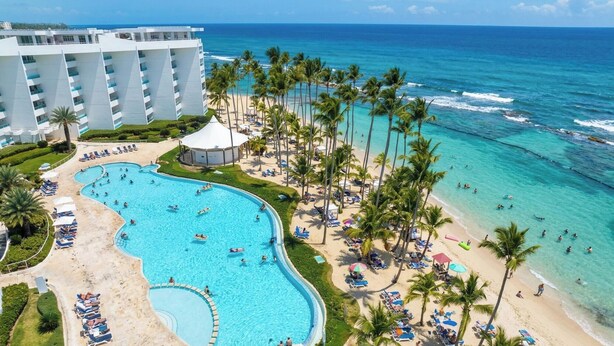 A resort with a large swimming pool, beach, and ocean view. - LuxuryCondo| Beachfront| AmazingView | FastWifi (Juan Dolio)