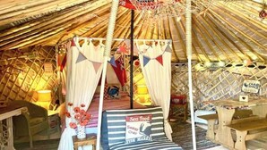 A cozy, well-lit tent with a bed, a small table, and a sign indicating a cold drink option. - 'Crab Shack' Luxury Yurt with Harbour & Sea Views (Emsworth)