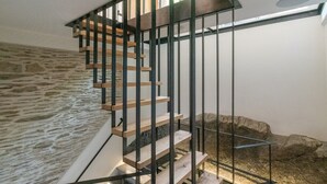 A staircase with wooden steps and black metal railings, leading to a stone wall. - Holiday Home in La Roche with Castle Views (la roche-en-ardenne)