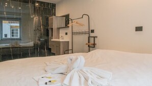 A hotel room with a large bed, a hanging clothes rack, a bathroom with a mirror, and a view of the outside. - Holiday Home in La Roche with Castle Views (la roche-en-ardenne)