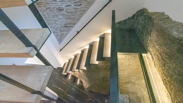 A modern interior with a stone wall, a staircase with white railings, and a ceiling with a unique texture. - Holiday Home in La Roche with Castle Views (la roche-en-ardenne)