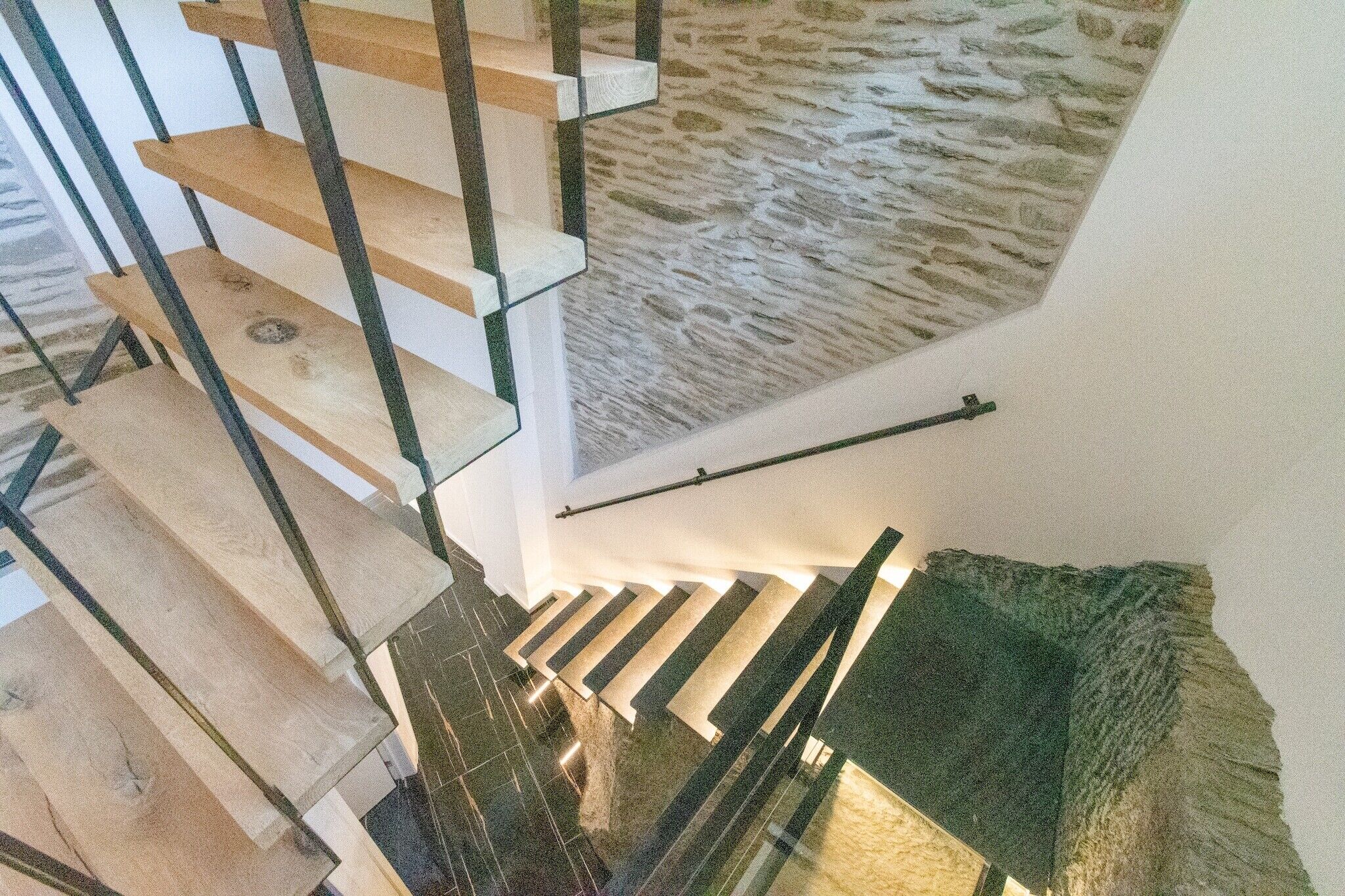 A staircase with wooden steps and a stone wall.
