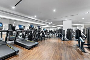 Ein Fitnessraum mit Laufbändern, Crosstrainern und Gewichten.