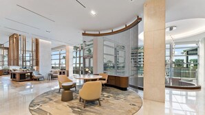 A spacious lobby with a round seating area, a glass wall, and a view of the outside. - Luxury Amrit Ocean Resort - 2BDR Condo (Riviera Beach)