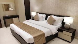 A modern hotel room with a large bed, two bedside tables, a nightstand, and a mirror. - شقق الشرفة للشقق المفروشة -AlSHORFA FURNISHED APARTMENT (Riyadh)
