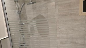 A glass-enclosed shower with a tiled wall and a small window. - شقق الشرفة للشقق المفروشة -AlSHORFA FURNISHED APARTMENT (Riyadh)
