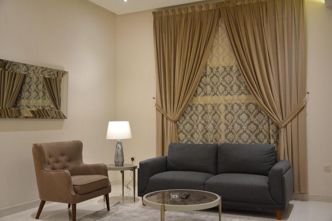 A living room with a grey sofa, a brown armchair, a small side table with a lamp, and a coffee table.
