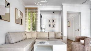 A modern living room with a sectional sofa, a white coffee table, and a patterned rug. - Whitewood Residence (Athens)