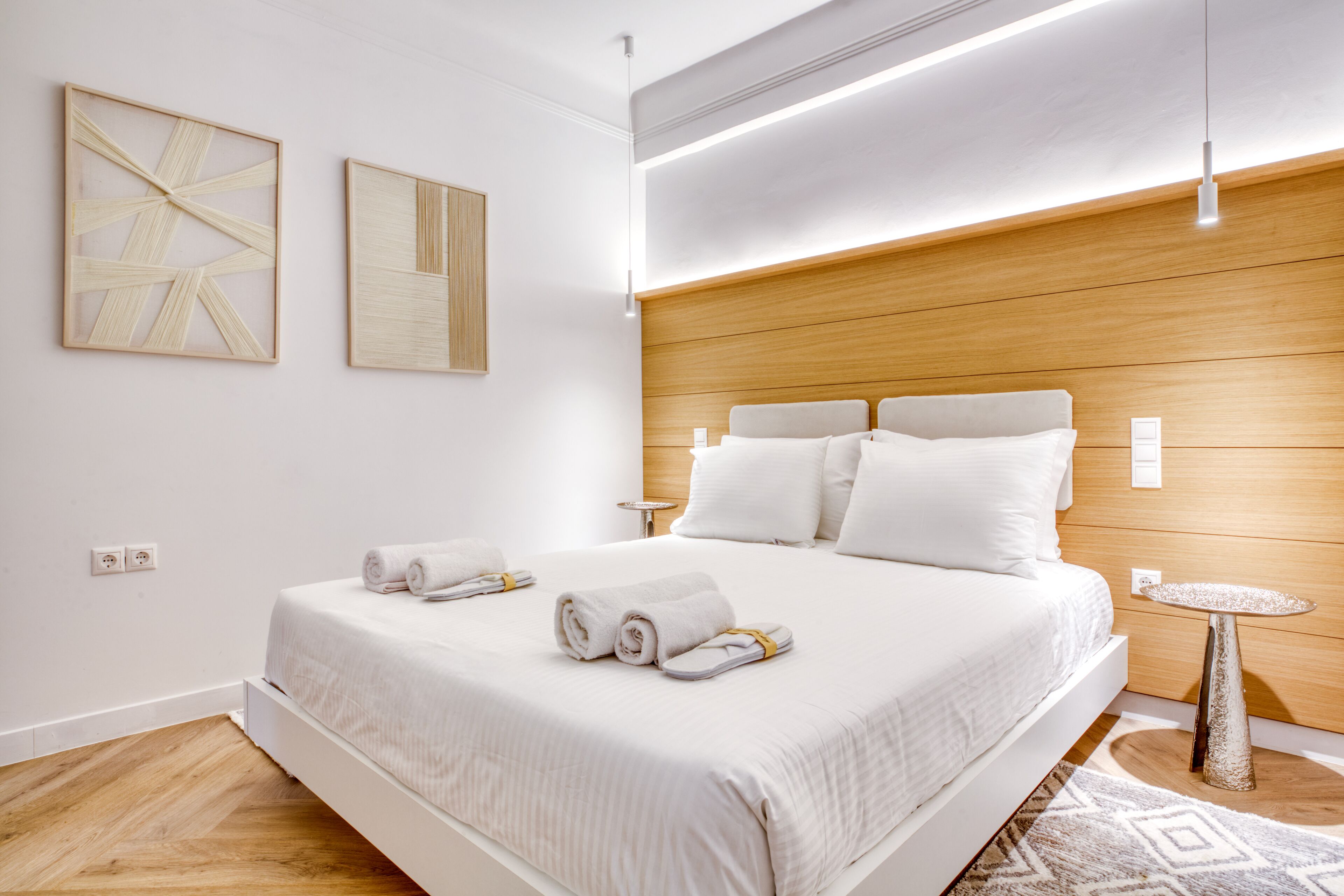 A modern hotel room with a large bed, wooden headboard, and two bedside tables.
