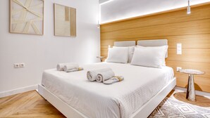 A modern hotel room with a large bed, wooden headboard, and two bedside tables. - Whitewood Residence (Athens)