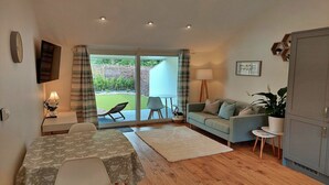 A living room with a dining table, sofa, and a view of the garden through a sliding door. - Cottage in Dartmoor with Private Hot Tub (Bovey Tracey)