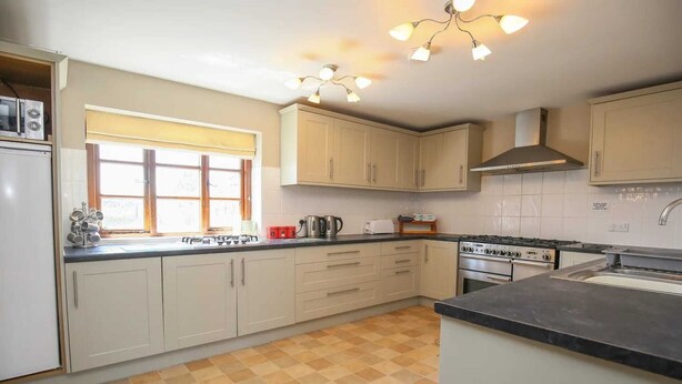 A kitchen with beige cabinets, a gas stove, an oven, and a sink. - Luxury cottage with pool & Tennis, No Deposit (Onibury)
