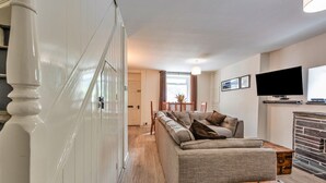 Ein Wohnzimmer mit einer Couch, einem Flachbildfernseher und einem Kamin.