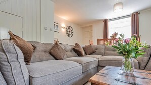 Ein modernes Wohnzimmer mit einer Eckcouch, einem Holztisch und einer Vase mit Blumen.