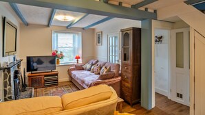 A cozy living room with a sofa, a television, and a cabinet. - Cottage in St Dennis near Eden Project (St Dennis)