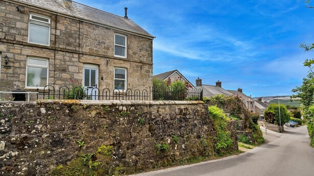 A stone building with a stone wall, a metal fence, and a clear blue sky. - Cottage in St Dennis near Eden Project (St Dennis)