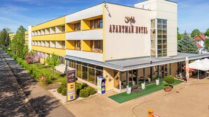 Un hôtel moderne à la façade jaune, doté d’un espace de réception et de sièges en plein air.