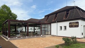Un bâtiment moderne doté d’une façade en verre et d’une enseigne indiquant « Pergola Étterem ».