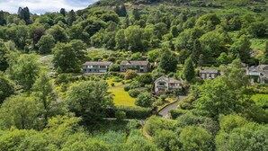 A residential area with houses surrounded by lush greenery and a hill in the background. - Cottage in Grasmere with Lake Access (Grasmere)
