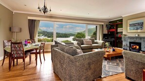 A living room with a fireplace, a dining area with a table and chairs, and a view of the outdoors. - Cottage in Grasmere with Lake Access (Grasmere)