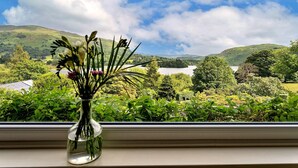 A window with a vase of flowers overlooking a scenic landscape. - Cottage in Grasmere with Lake Access (Grasmere)